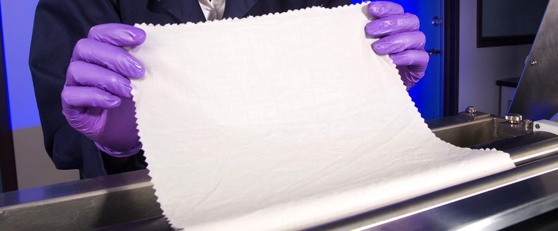 A chemist treating a piece of cotton fabric with a chitosan formulation.