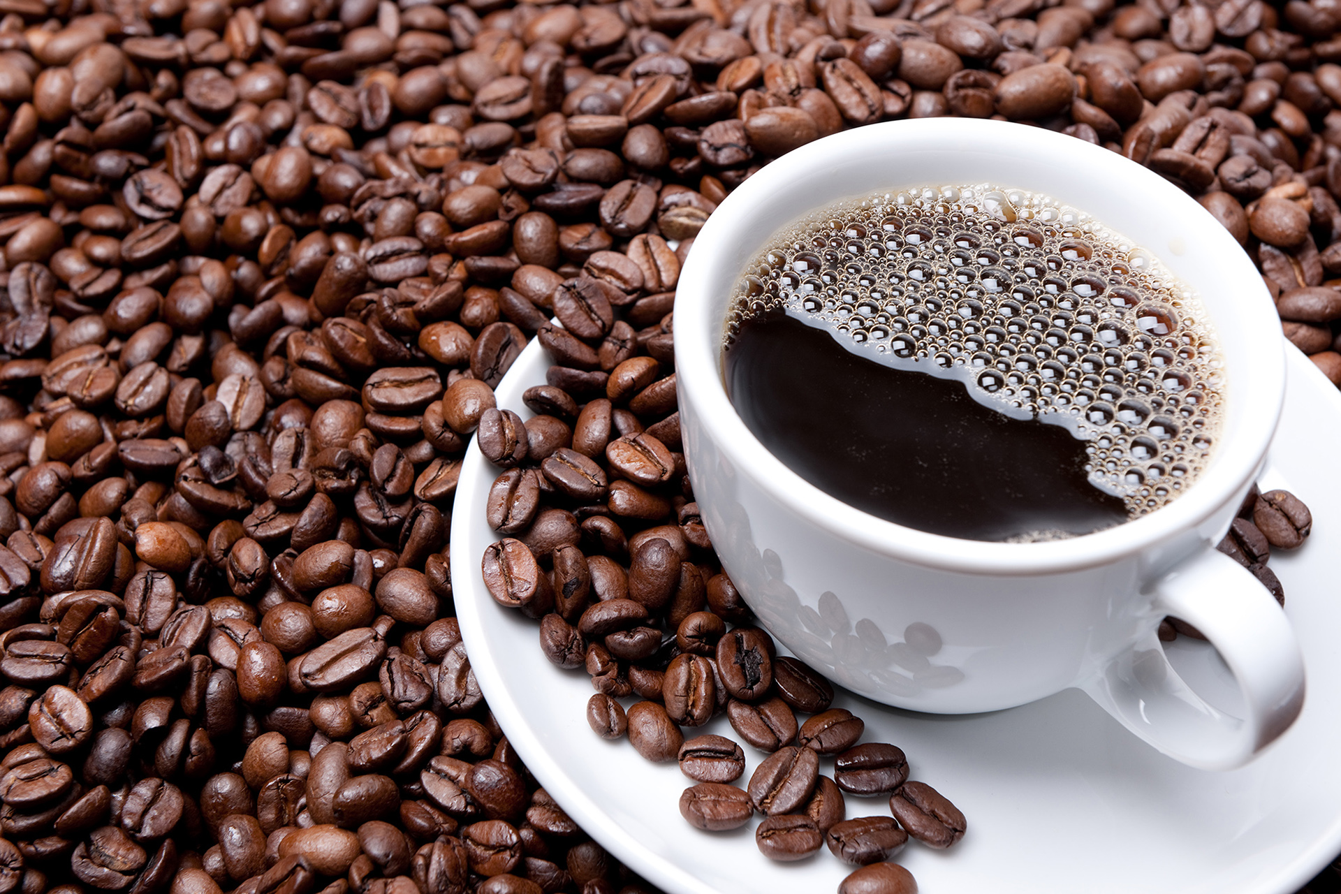 A cup of coffee in a pile of coffee beans