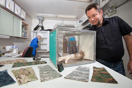 Uniforms A scientist putting his arm in a box containing mosquitoes