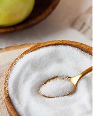 A spoon scooping sugar from a bowl 