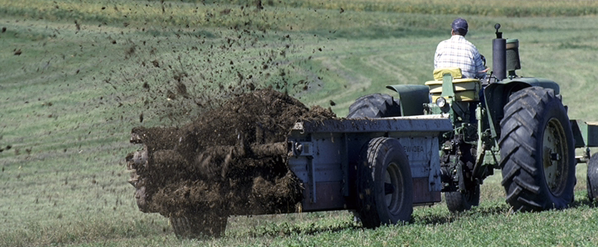 A farmer using a tractor to spread fertilizer