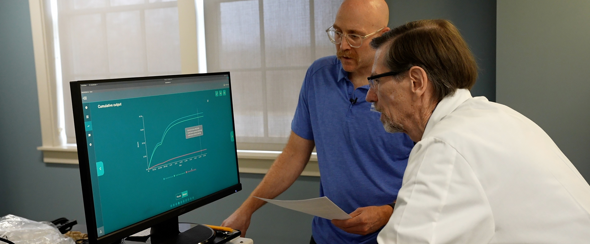 Two scientists look at a computer screen. 