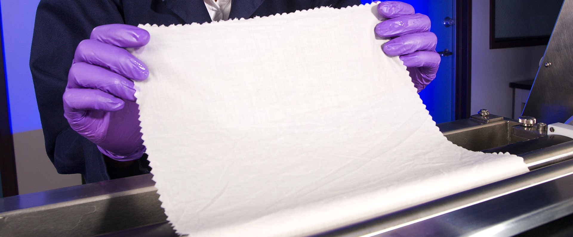 A chemist treating a piece of cotton fabric with a chitosan formulation.