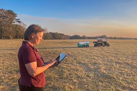 Dr. Galina Yakubova in a field monitoring real-time measurements of soil carbon, captured by the Mobile Inelastic Neutron Scattering scanning system. 