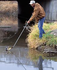 Technician collecting a water sample from Walnut Creek 
