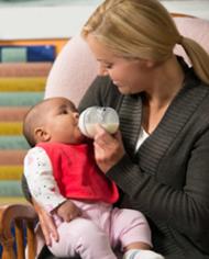 A woman bottle feeding an infant